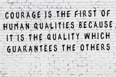 Beyaz tuğla duvara zekice alıntılar yazılı siyah bir yazı.