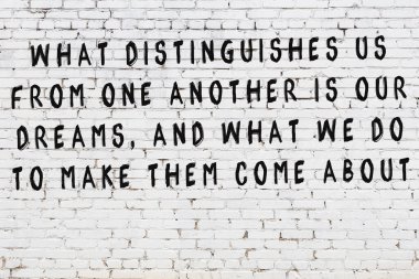 Beyaz tuğla duvar arkaplanına siyah düşünceli bir yazı.