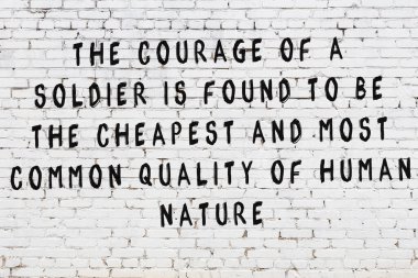 Beyaz tuğla duvara zekice alıntılar yazılı siyah bir yazı.