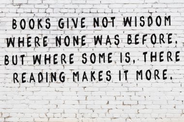 Beyaz tuğla duvara zekice alıntılar yazılı siyah bir yazı.