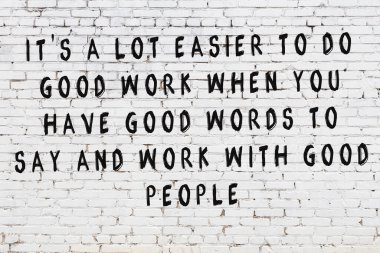 Beyaz tuğla duvara zekice alıntılar yazılı siyah bir yazı.