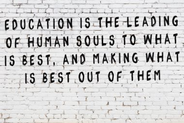 Beyaz tuğla duvara zekice alıntılar yazılı siyah bir yazı.