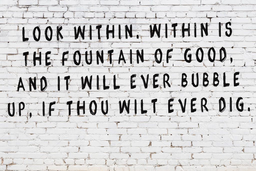 White brick wall with painted black inscription of wise quote