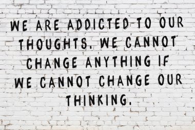 Beyaz tuğla duvar arkaplanına siyah düşünceli bir yazı.