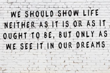 Beyaz tuğla duvar arkaplanına siyah düşünceli bir yazı.