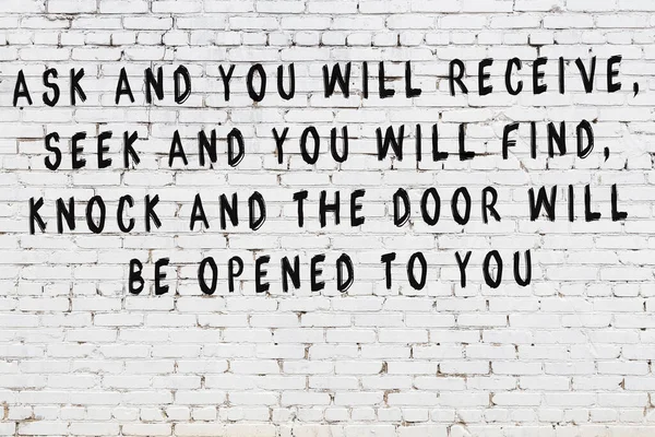 Стена из белого кирпича с покрашенной черной надписью мудрой цитаты — стоковое фото