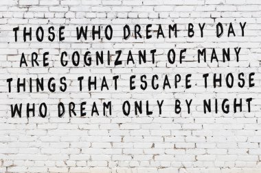 Beyaz tuğla duvar arkaplanına siyah düşünceli bir yazı.