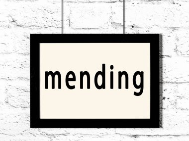 Beyaz tuğla duvarda asılı siyah çerçeve ve yazı onarımı