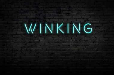 Tuğla duvardaki neon ışıklarının gece görüşü ve yazıtlar göz kırpıyor.