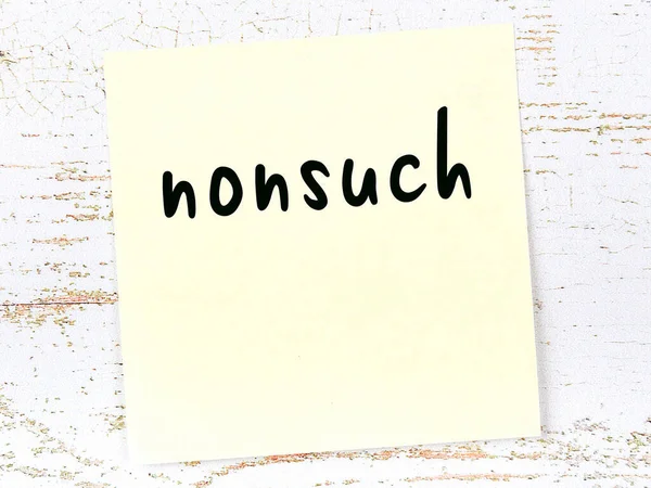 Yellow sticky note on wooden wall with handwritten word nonsuch