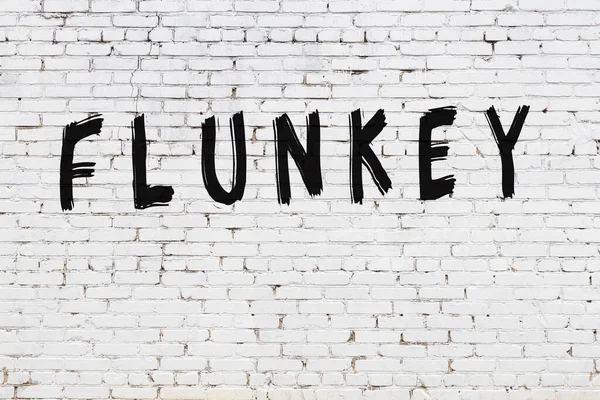 Napis flunkey malowany na białej ceglanej ścianie — Zdjęcie stockowe