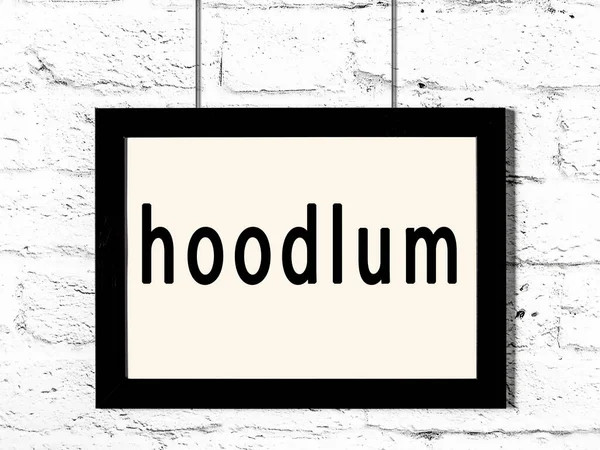 Quadro preto pendurado na parede de tijolo branco com inscrição hoodlum — Fotografia de Stock