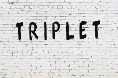 Beyaz tuğla duvara yazılmış üçlü yazı.