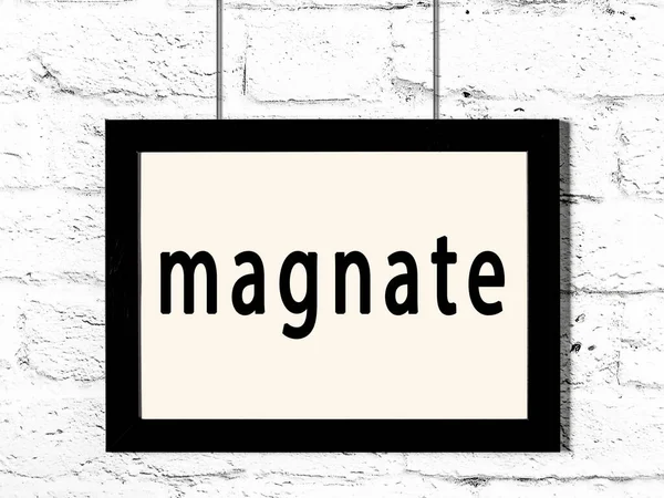 Μαύρο πλαίσιο κρέμεται σε λευκό τοίχο τούβλο με επιγραφή magnate — Φωτογραφία Αρχείου