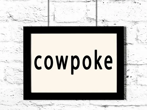 Quadro preto pendurado na parede de tijolo branco com inscrição cowpoke — Fotografia de Stock