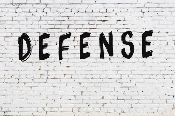 White wall with black paint inscription defense on it
