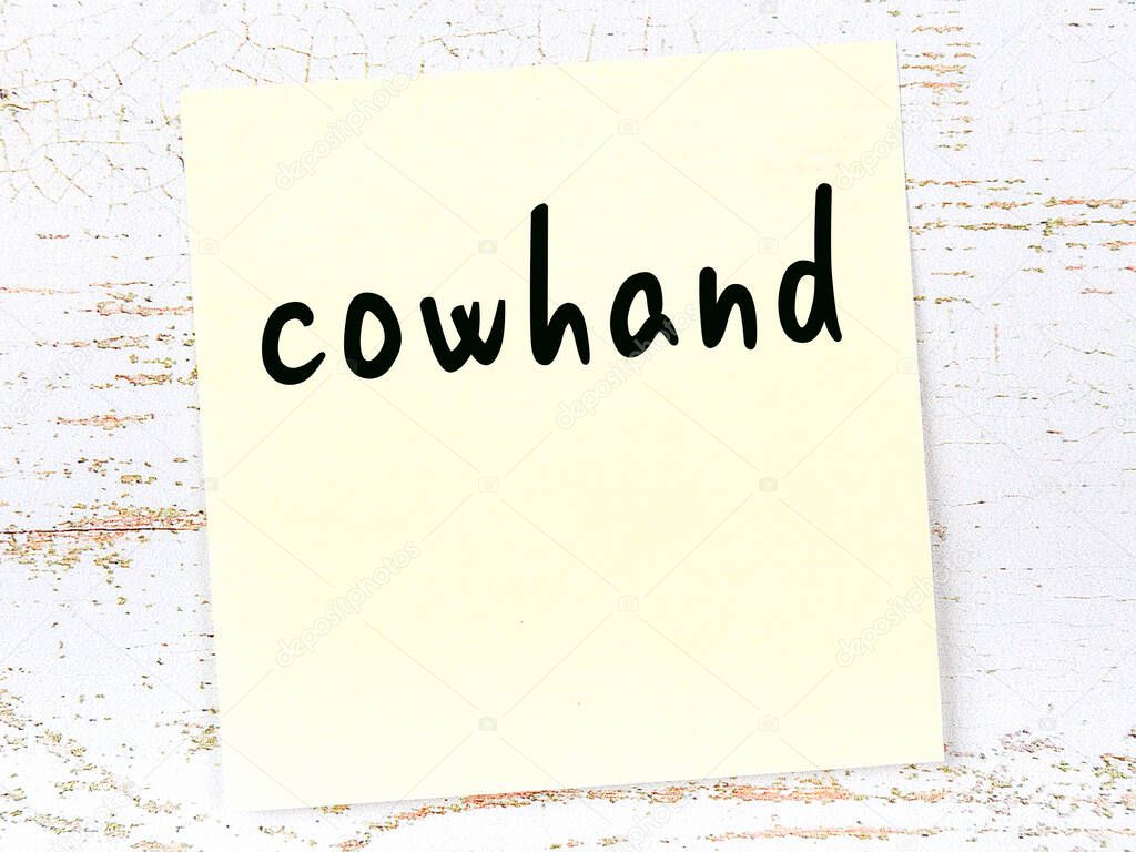 Yellow sheet of paper with word cowhand. Reminder concept