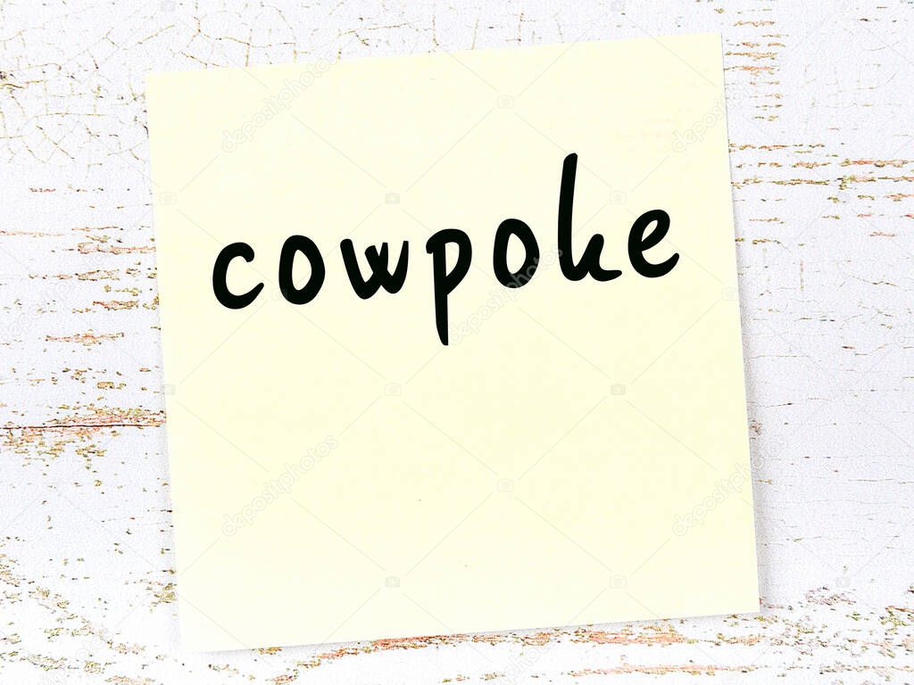 Yellow sheet of paper with word cowpoke. Reminder concept