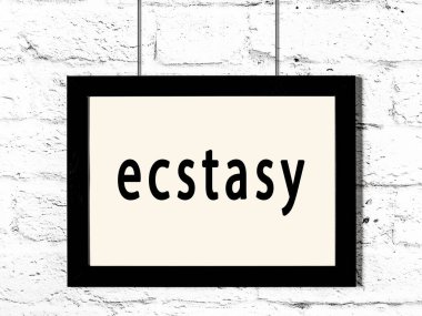 Beyaz tuğla duvarda asılı siyah çerçeve ve ekstazi.