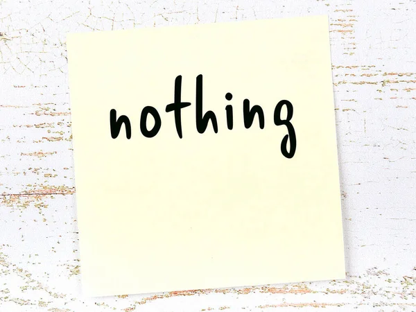 Żółta kartka papieru ze słowem "nic". Koncepcja przypomnienia — Zdjęcie stockowe
