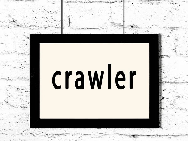 Zwart frame opknoping op witte bakstenen muur met inscriptie crawler — Stockfoto