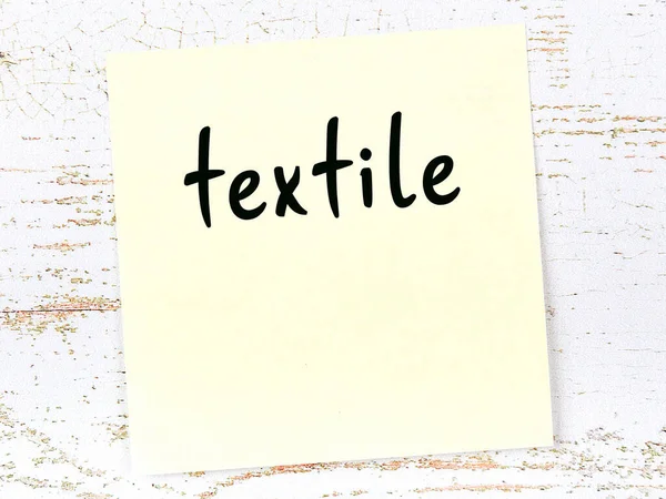 Hoja amarilla de papel con palabra textil. Concepto de recordatorio — Foto de Stock