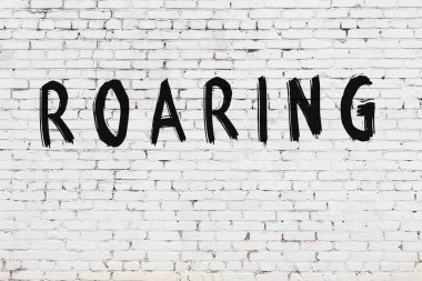 Beyaz tuğla duvarda kükreyen yazı.