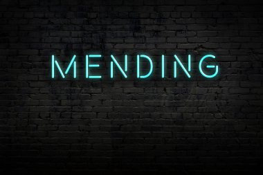 Neon işareti. Kelimeler tuğla duvara karşı işliyor. Gece görünümü