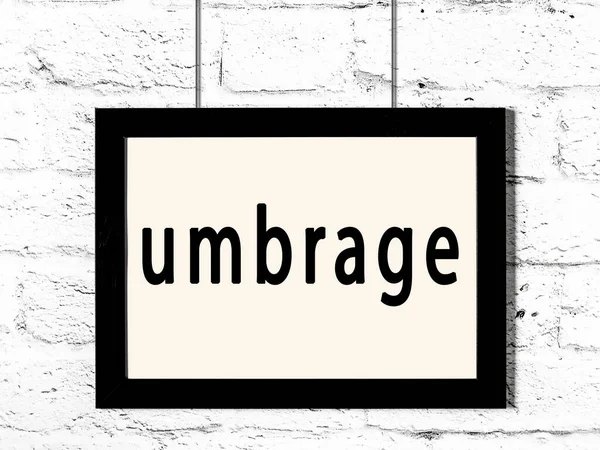 Black frame hanging on white brick wall with inscription umbrage — Stock Photo, Image