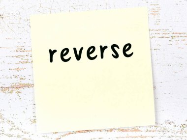 Tahta duvarda el yazısıyla tersten yazılmış sarı yapışkan bir not var.