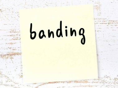 Tahta duvarda el yazısı bantlı sarı yapışkan bir not.