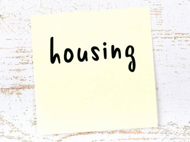 Tahta duvarda el yazısıyla yazılmış sarı yapışkan bir not var.