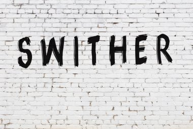 Beyaz tuğla duvara yazıtlar çizilmiş.