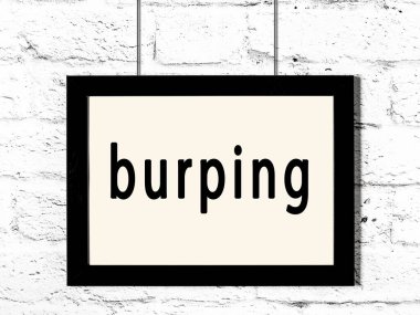 Beyaz tuğla duvarda asılı siyah çerçeve ve yazılı geğirme.