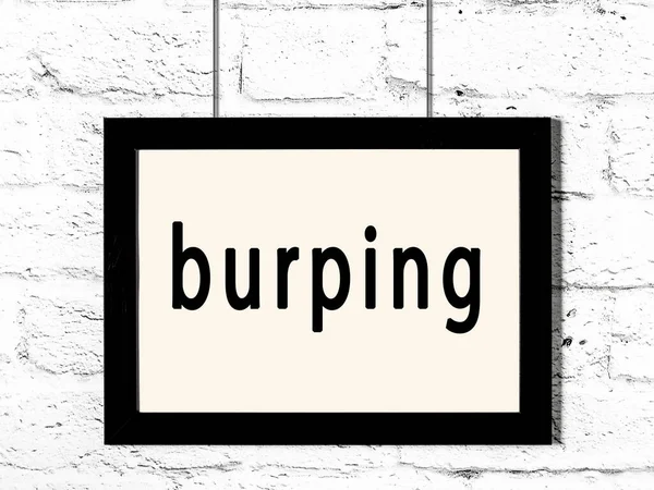 Beyaz tuğla duvarda asılı siyah çerçeve ve yazılı geğirme.