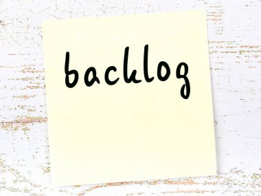 Tahta duvardaki sarı yapışkan notta el yazısı birikmiş sözcükler var.