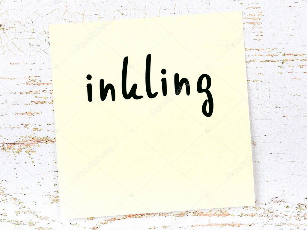 Yellow sticky note on wooden wall with handwritten word inkling