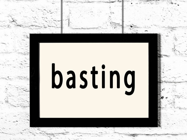 Black frame hanging on white brick wall with inscription basting