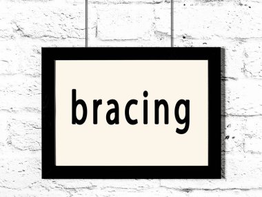 Beyaz tuğla duvarda asılı siyah çerçeve ve yazı destekleyici