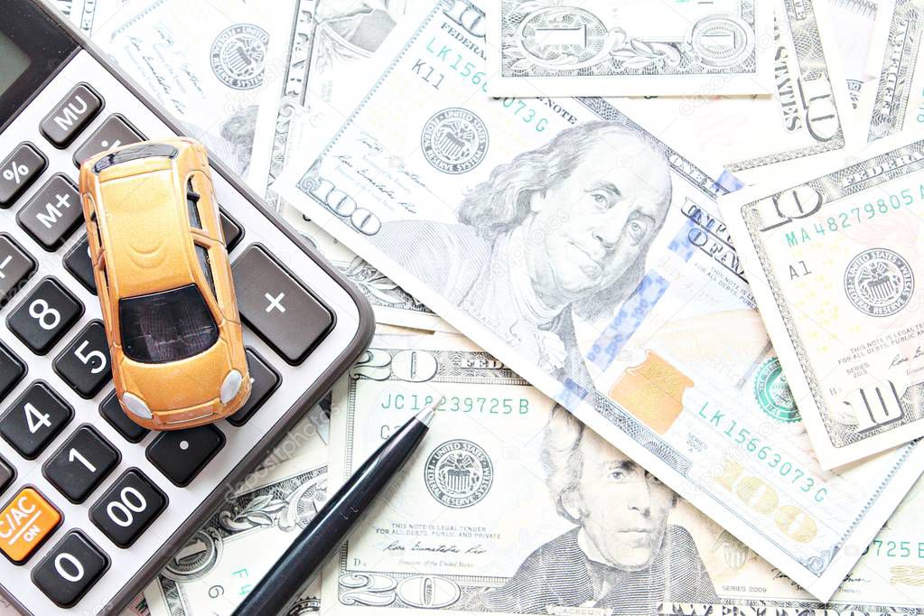 Business, finance, saving money, banking or car loan concept : Top view or flat lay of miniature car model, calculator and pen on American Dollars cash money 