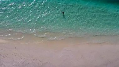 Mavi göl ve beyaz kum arka planındaki sakin sahil yolculuğunun insansız hava aracı görüntüsü