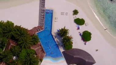 Mavi yeşil deniz ve beyaz kum arka planıyla cennet gibi bir sahil tatili manzarası.