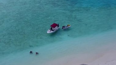 Lüks tatil beldesinin beyaz kumlu arka planlı sığ okyanus kıyısına yapılan hava aracı yolculuğu.