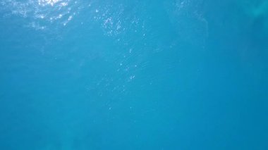 Mavi deniz ve beyaz kum arka planının mükemmel sahil yolculuğunun insansız hava yolculuğu.
