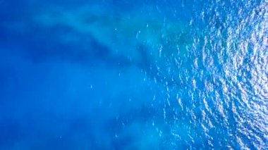 Mavi yeşil su ve beyaz kumlu arka planda sakin sahil gezisinin insansız hava aracı görüntüsü