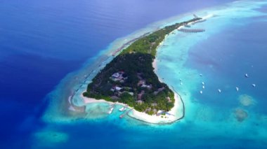 Mavi deniz kıyısındaki güzel tatil köyü manzarası ve parlak kum arka planı.