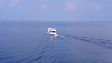 Rahatlatıcı sahil manzarası mavi deniz ve parlak kumlu zemin tarafından kırılıyor.