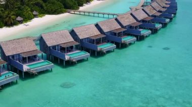 Lüks deniz manzarasının insansız hava aracı dokusu beyaz kum arka planıyla berrak deniz tarafından kırılıyor.