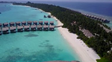 Lüks tatil köyü sahil saatinin insansız hava aracı manzarası beyaz kum arka planlı mavi yeşil su