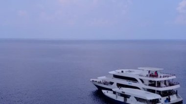 Mavi deniz kıyısında beyaz kumlu arka planda sakin sahil yolculuğunun insansız hava aracı soyutlaması.